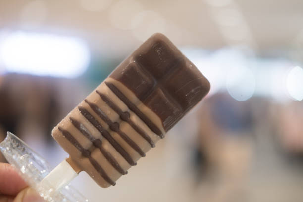 istock Coffee ice cream on a stick in young hand 1185591219