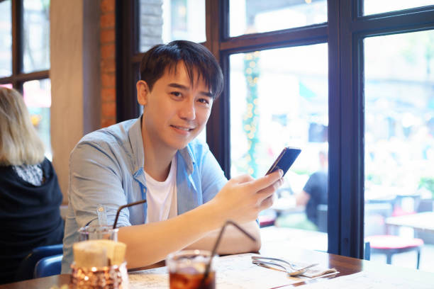 istock young asian man using smart phone in restaurant 1185593827