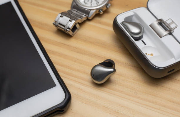 istock Silver true wireless bluetooth earphones with charging case and moblie phone. Bleach color effect 1185595222