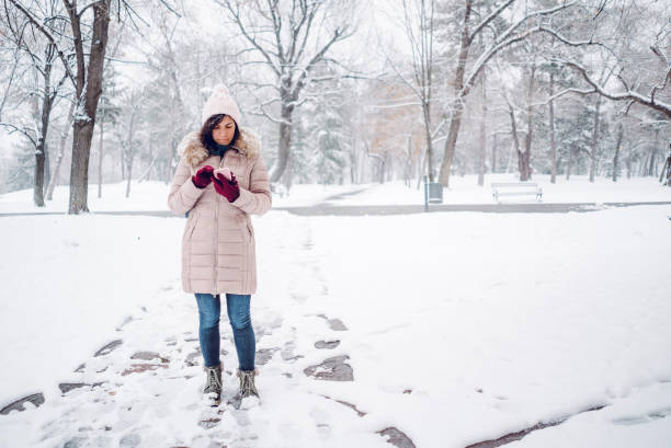 istock Woman using phone in the snow 1185598885