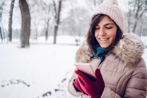 istock Woman using phone in the snow 1185598937
