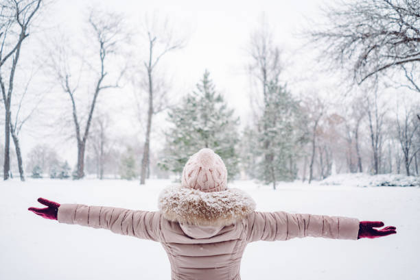 istock Woman spreading hands in a snow covered park 1185599095