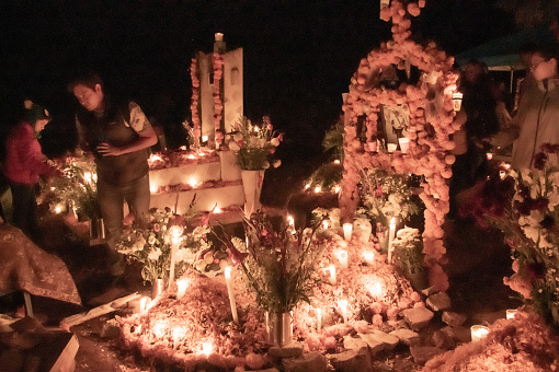 A cemetery in Michoacan, Mexico - A Day of the Dead tradition in Mexico is to celebrate and honor the deceased loved ones in a family. Graves are elaborately decorated and families light candles and hold vigils in honor of their loved ones. They bring their small children and babies and stay hours at the gravesites.