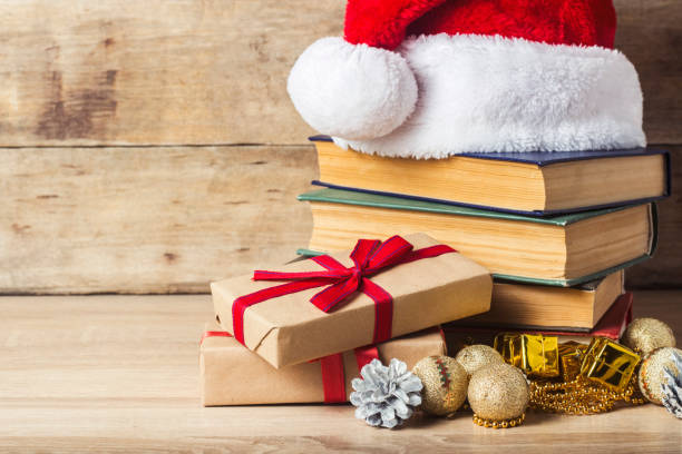 istock A stack of books, Santa Claus's cap, an alarm clock, cones, Christmas-tree decorations, gift boxes on a wooden background. Concept of New Year and Merry Christmas. 1185603085