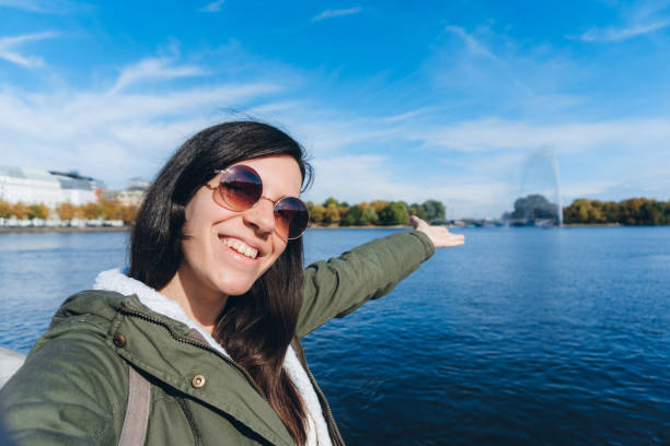 Young beautiful caucasian woman making selfie at lake for her social media fans.