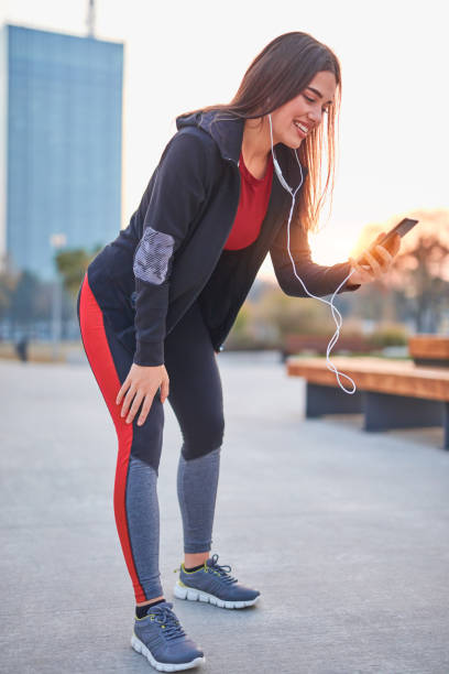 istock Modern young woman with cellphone making pause during jogging / exercise. 1185609193