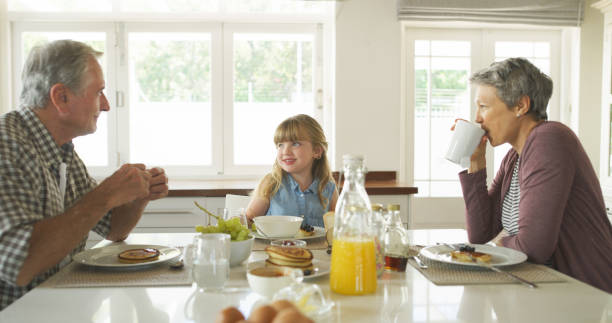 Shot of a little girl having breakfast with her grandparents at home