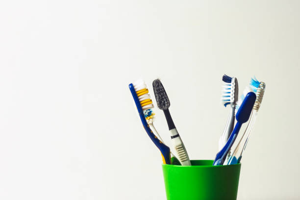 Many toothbrushes in a plastic cup on a white background. The concept of changing toothbrushes, oral hygiene, dentistry, a large and friendly family.