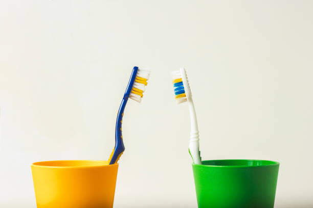 istock Two used toothbrushes in two plastic cups on a white background. The concept of changing toothbrushes, oral hygiene, dentistry, friendly family, joint life, relocation, love, acquaintance. 1185612308