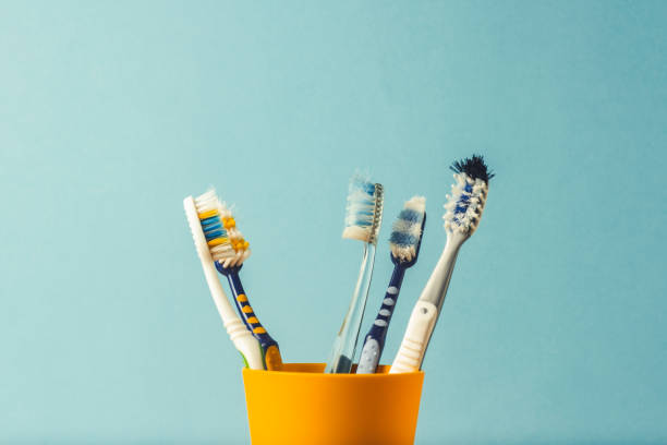 istock Many toothbrushes in a plastic cup on a blue background. The concept of changing toothbrushes, oral hygiene, dentistry. Big and friendly family. 1185612321
