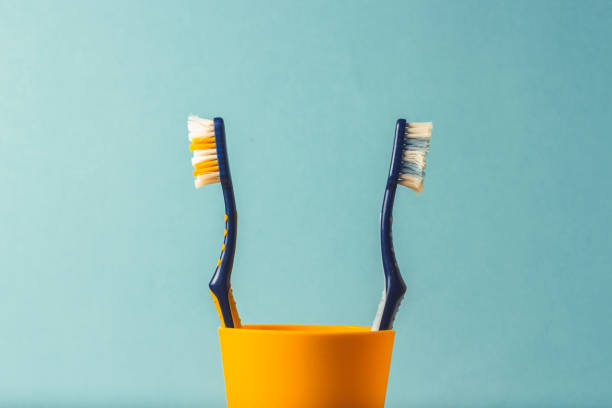 istock Two toothbrushes in a plastic cup are turned away from each other on a blue background. The concept of changing toothbrushes, oral hygiene, dentistry. Family quarrel, divorce, misunderstanding. 1185612924