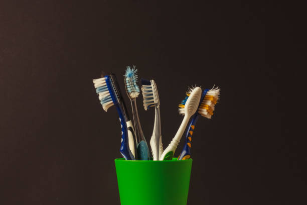 istock Many toothbrushes in a plastic cup on a black background. The concept of changing toothbrushes, oral hygiene, dentistry. Big and friendly family. 1185612947