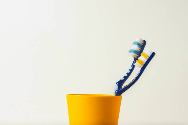 Two used toothbrushes in a plastic cup on a white background. The concept of changing toothbrushes, oral hygiene, dentistry, friendly family.