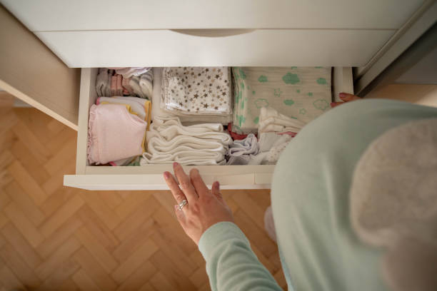 Looking forward about being a mom soon High angle view of unrecognizable woman looking at neatly folded baby clothes. baby clothing stock pictures, royalty-free photos & images