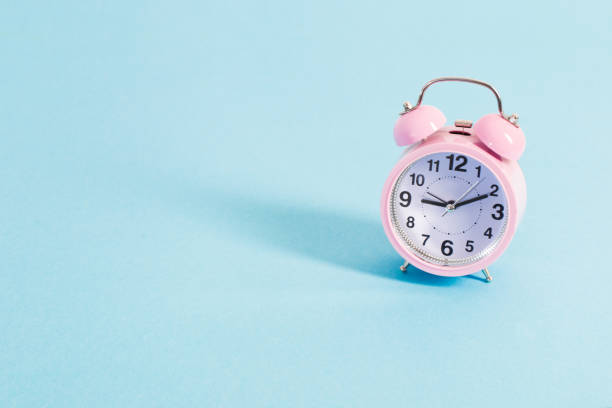 istock pink alarm clock on blue background 1185614063
