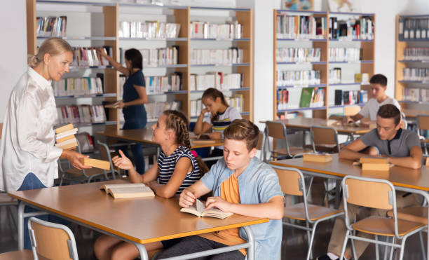 istock Friendly teenage schoolers reading and writing 1185615575