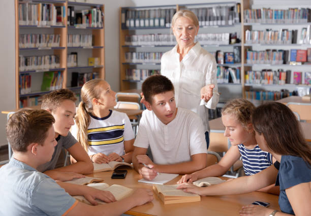 istock Group of glad schoolers discussing with teacher 1185615614