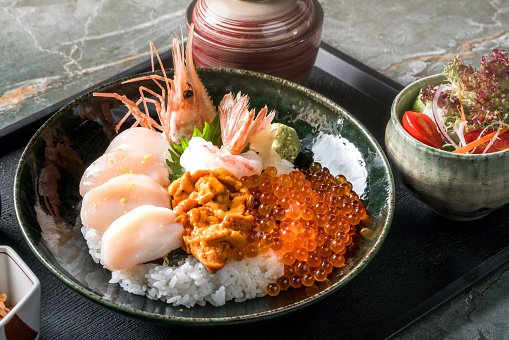 Kaisen Don (Sashimi seafood Rice Bowl) served with sushi and salmon rolls , Japanese food.