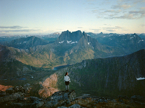 Young Caucasian woman standing and looking at scenic view in Senja Island from mountains