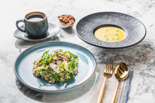 Italian cheese risotto on white plate. Creamy risotto topped parmesan cheese and espuma. Italian risotto with cheese on light background with shadows of leaves. Simple italian menu