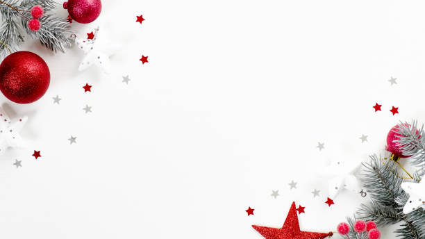 istock Christmas tree branches with red balls and stars over white background with confetti. Christmas greeting card mockup, winter holiday postcard template 1185621393