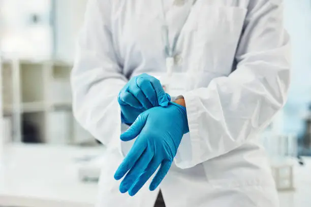 Closeup shot of scientist putting on protective gloves in a lab