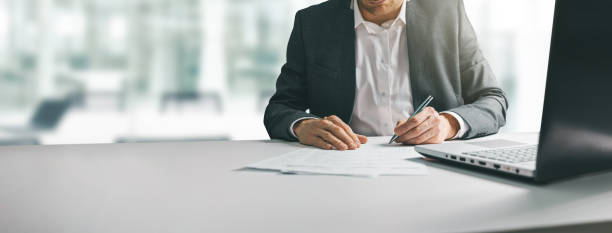 joven en traje escribiendo artículos de negocios en el escritorio en la oficina de coworking moderna. copiar espacio - pen contract writing signature fotografías e imágenes de stock