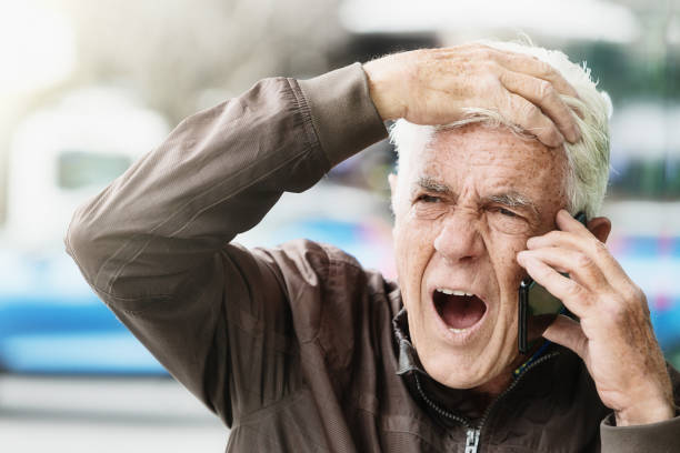 яростно сердитый старший человек кричит в мобильный телефон - furiously стоковые фото и изображения