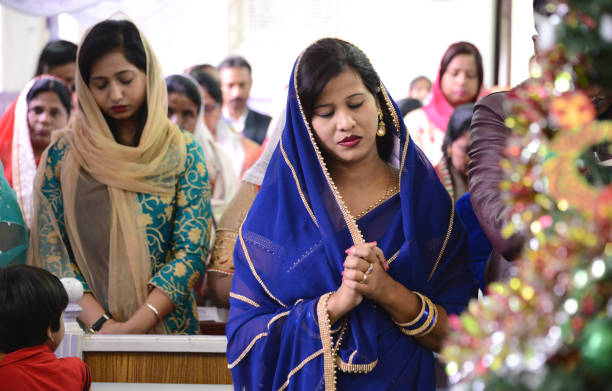 An Indian mother and her daughters are praying in their living room together. They are peaceful as they rest in prayer pose. They are connecting with their god and giving thanks.