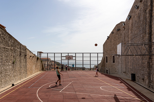 Dubrovnik, Croatia - April 24, 2019:  Basketball court in  historical medieval city centre of  Dubrovnik, Croatia with in the background the Adriatic Sea.