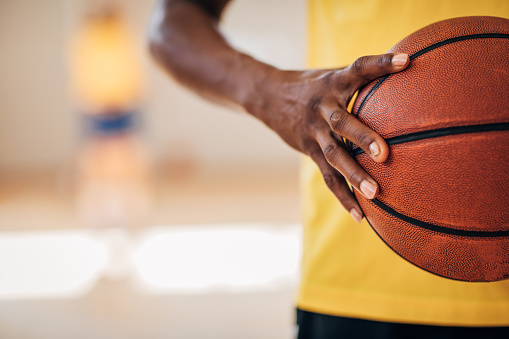 One woman, black lady basketball player holding a basketball ball indoors.