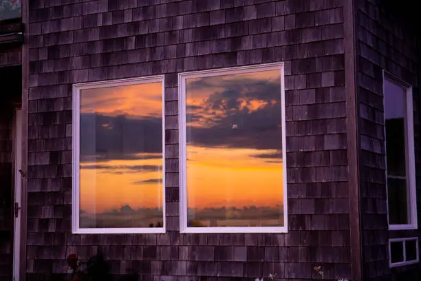 Photo of The sun reflects itself in the windows of beachfront homes in the pacifi coast; beautiful, dramatic skies and colors; golden light. Artistic editing and outtake.