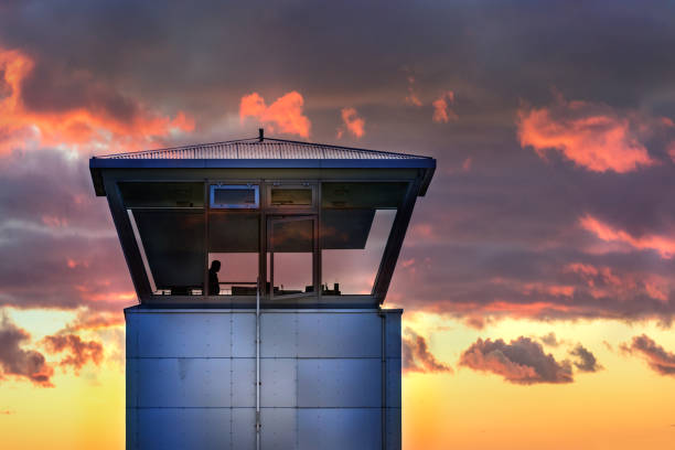 una torre di controllo del traffico aereo con la sagoma del controllore del traffico maschile, tempo nuvoloso, islanda. - air traffic control tower foto e immagini stock