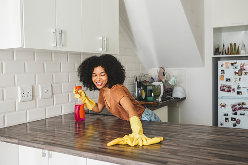 Cropped shot of a young woman wearing rubber gloves while cleaning her home