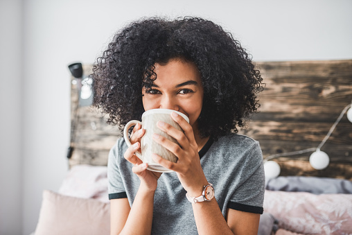 Cropped shot of a young woman enjoying a hot beverage while sitting in her room