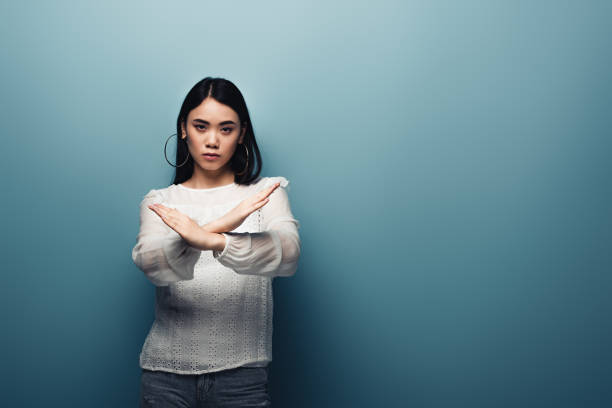 istock upset brunette asian woman showing stop gesture on blue background 1185641499