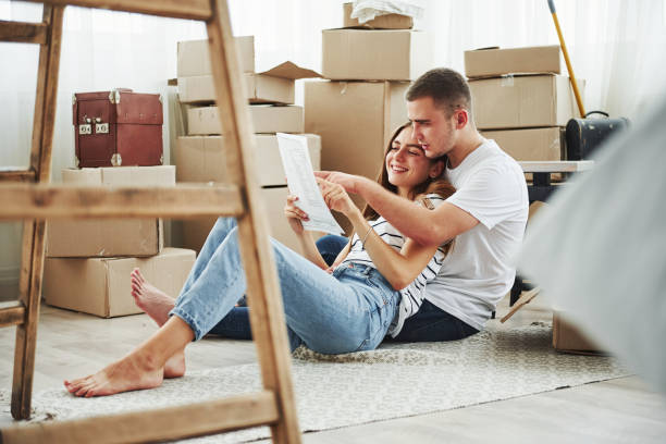 istock Reading document. Cheerful young couple in their new apartment. Conception of moving 1185641516