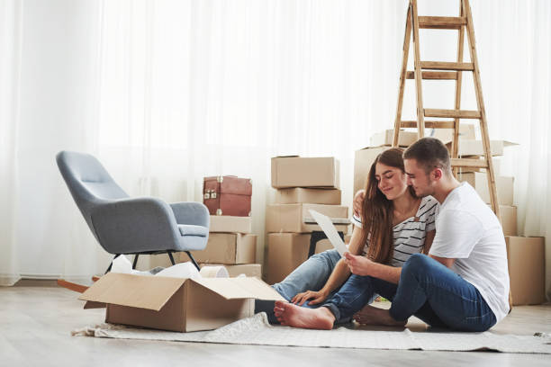 istock Empty room with boxes and ladder. Cheerful young couple in their new apartment. Conception of moving 1185641643