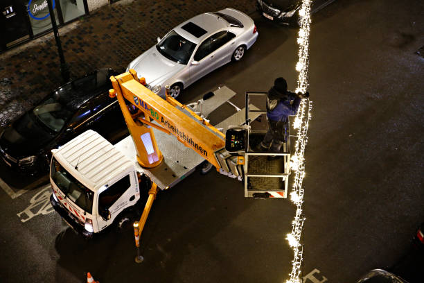 Municipal workers on the crane bucket truck install and decorate with Christmas Lights a street in Brussels Municipal workers on the crane bucket truck install and decorate with Christmas Lights a street in Brussels, Belgium on Nov. 24, 2018. Christmas light installation service stock pictures, royalty-free photos & images