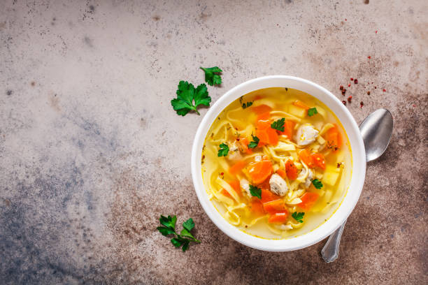 istock Chicken noodle soup with parsley and vegetables in a white plate, top view. 1185644431