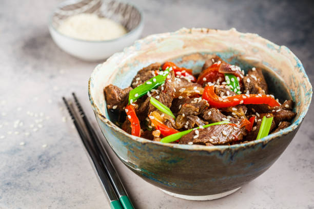istock Asian teriyaki beef with green onions and sesame seeds in beautiful bowl, gray background. 1185646096
