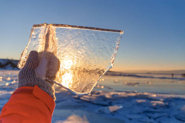 Winter landscape,Sun shines through clear ice chunk in a hand, Lake Baikal, Siberia, Russia. stock photo
