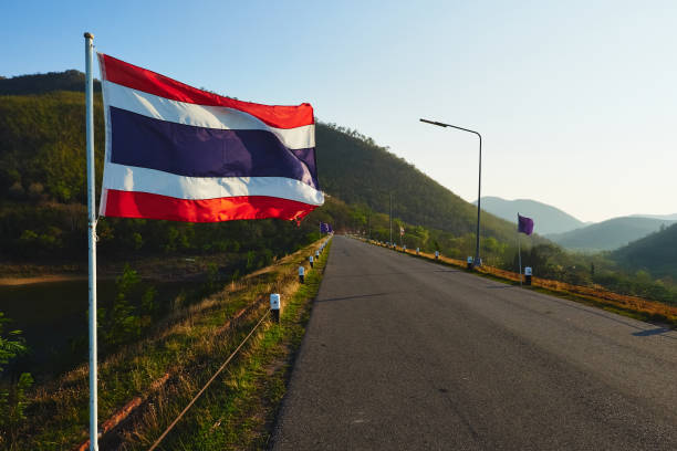 A Thailand flag waving against a mountain range. stock photo