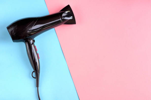 istock Black hair dryer on blue and pink background composition. 1185647989
