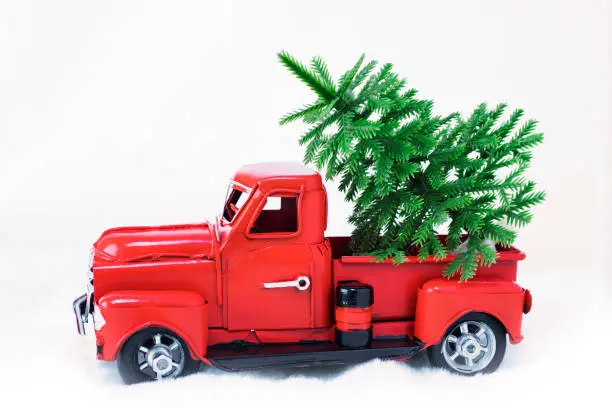 Photo of Green spruce in a red Christmas truck on a white background. Concept - greeting card for Christmas and New Year, holiday delivery. Copy space