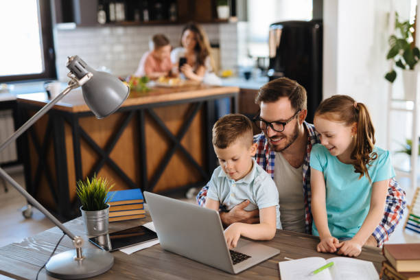 istock Father with daughter and son on his lap using laptop at home 1185648607