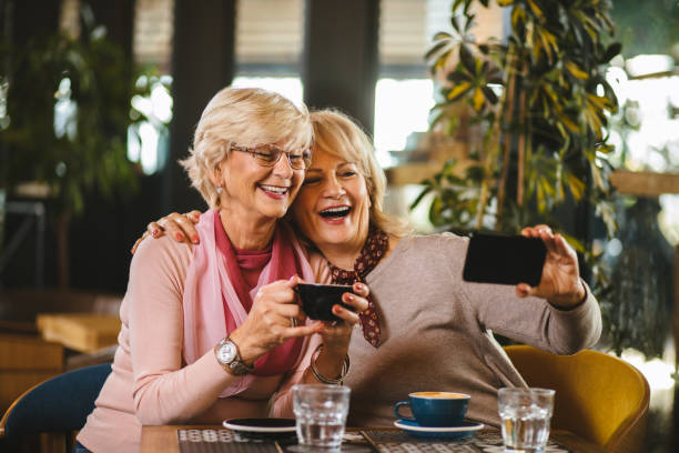 istock Two senior ladies taking selfie with smart phone in cafe 1185648947