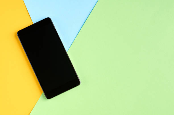istock Black cellphone on yellow and blue background composition, mobile phone. 1185649031