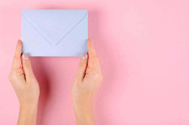 istock Hand with blue paper envelope composition on pink background. 1185650345