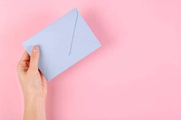 istock Hand with blue paper envelope composition on pink background. 1185650360